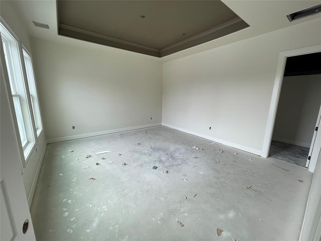 spare room with a tray ceiling, baseboards, and visible vents