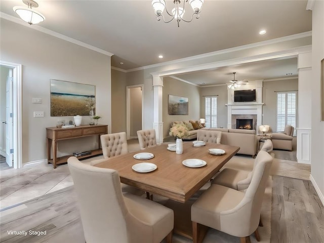 dining space with ceiling fan with notable chandelier, a fireplace, light hardwood / wood-style floors, and crown molding