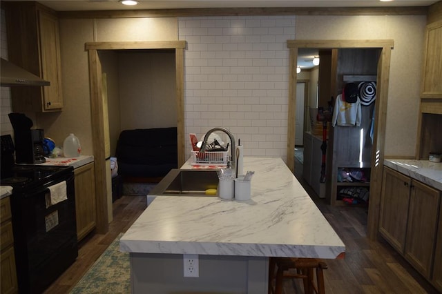 kitchen with light countertops, black range with electric stovetop, wall chimney exhaust hood, dark wood finished floors, and a sink