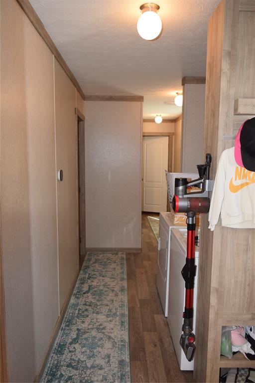 hall with washing machine and dryer, wood finished floors, and ornamental molding