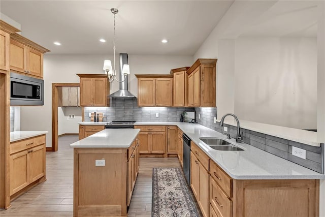 kitchen with wall chimney range hood, sink, hanging light fixtures, a kitchen island, and stainless steel appliances