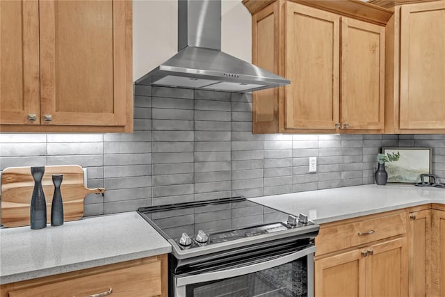 kitchen with decorative backsplash, light stone countertops, stainless steel range with electric stovetop, and wall chimney range hood