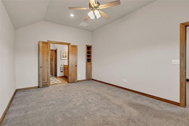 unfurnished bedroom featuring a walk in closet, ensuite bathroom, ceiling fan, a closet, and lofted ceiling