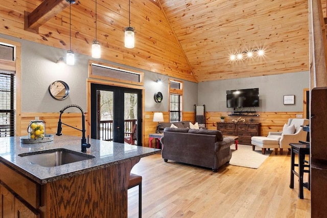 living room with wood ceiling, light hardwood / wood-style floors, wooden walls, and sink