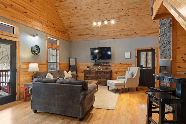 living room featuring light wood-type flooring, wood ceiling, and wood walls