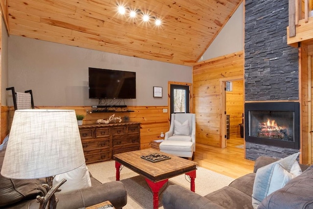 living room featuring a fireplace, wooden walls, light hardwood / wood-style floors, and wooden ceiling