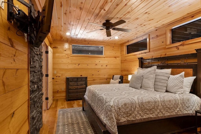 bedroom with ceiling fan, wood-type flooring, wood ceiling, and wooden walls