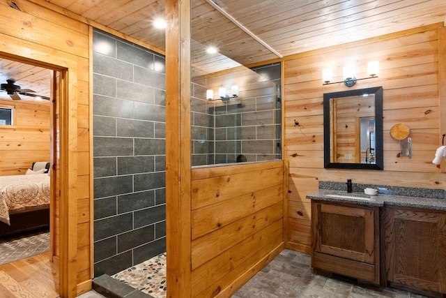 bathroom with ceiling fan, vanity, wood ceiling, and wood walls