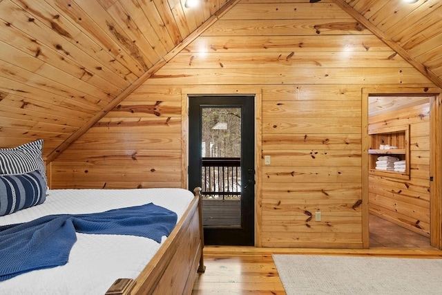 bedroom with vaulted ceiling, wood ceiling, wooden walls, and light hardwood / wood-style flooring