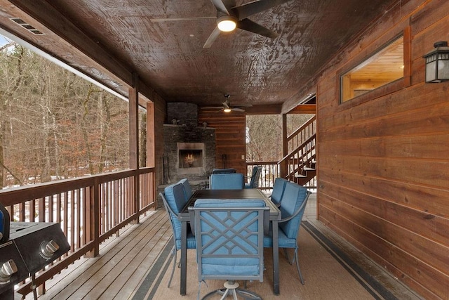 wooden terrace featuring ceiling fan and an outdoor stone fireplace