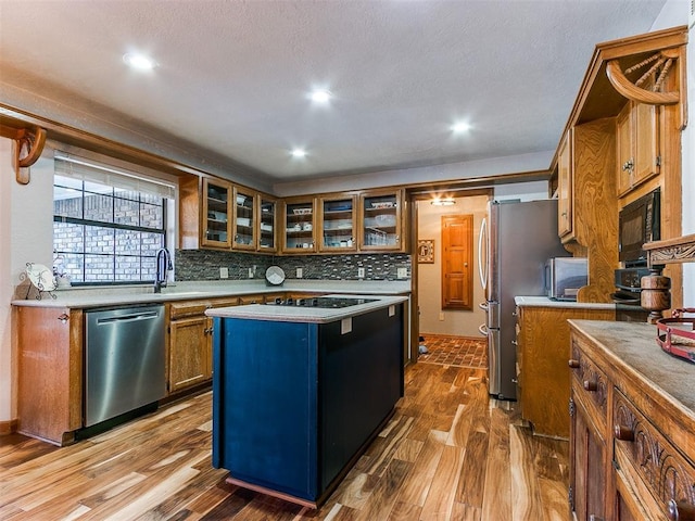 kitchen with a kitchen island, stainless steel appliances, sink, backsplash, and hardwood / wood-style flooring