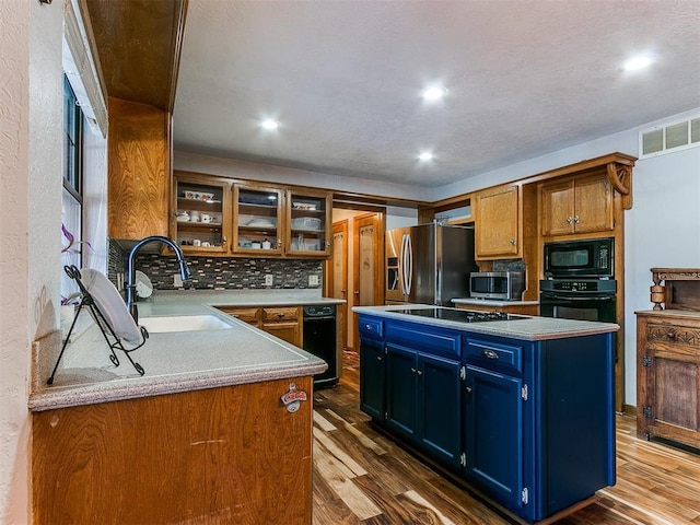 kitchen featuring dark hardwood / wood-style floors, blue cabinetry, a center island, black appliances, and sink