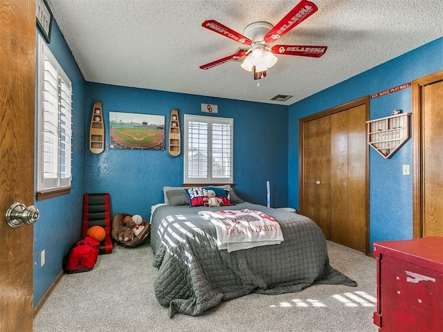 bedroom with ceiling fan, carpet, a closet, and a textured ceiling