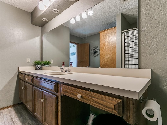 bathroom featuring a textured ceiling, wood-type flooring, and vanity