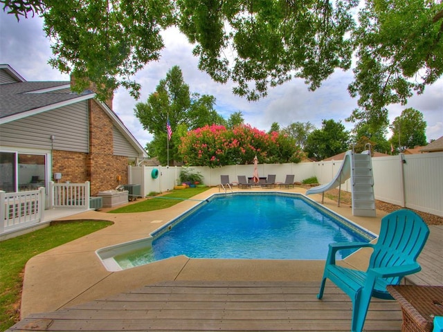 view of swimming pool with central AC unit, a patio area, and a water slide