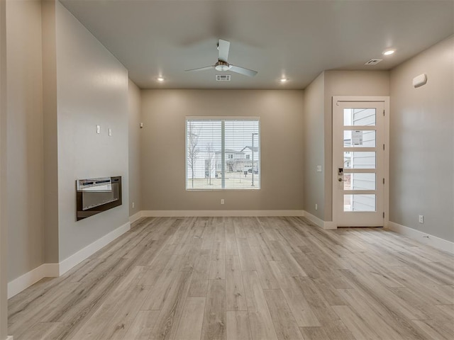 unfurnished living room with ceiling fan, heating unit, and light hardwood / wood-style floors