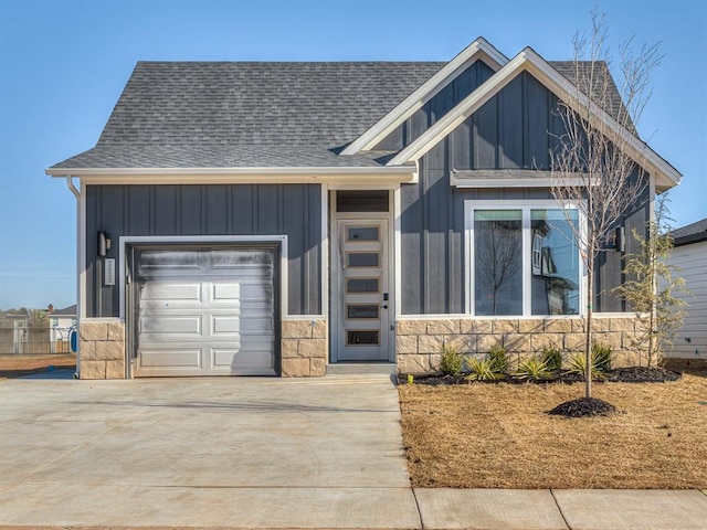 view of front of home featuring stone siding, board and batten siding, a garage, and roof with shingles