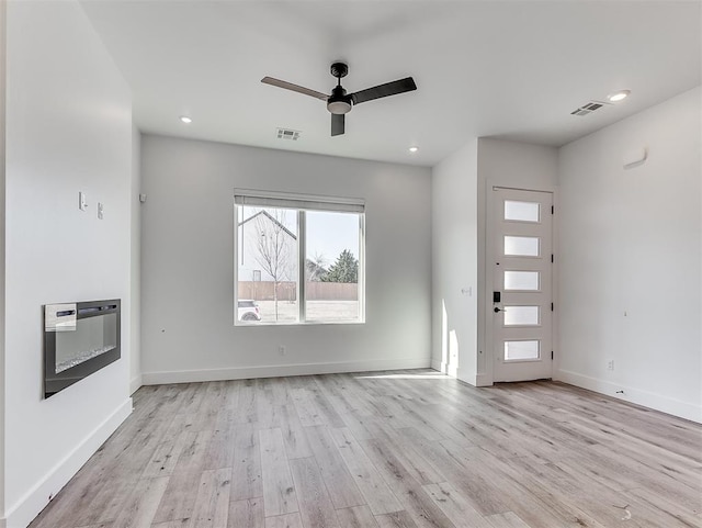 unfurnished living room with heating unit, visible vents, and light wood-type flooring