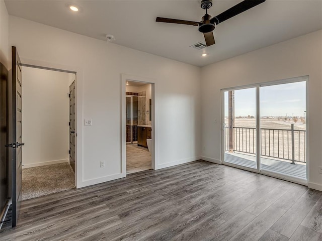 unfurnished bedroom featuring ensuite bathroom, ceiling fan, access to exterior, and hardwood / wood-style floors