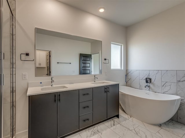 bathroom with tile walls, a tub to relax in, and vanity