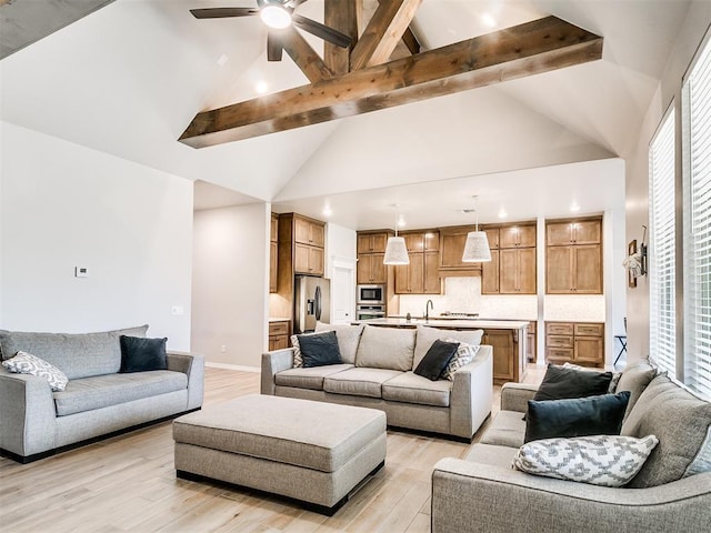 living room featuring light hardwood / wood-style floors, ceiling fan, a healthy amount of sunlight, high vaulted ceiling, and beamed ceiling