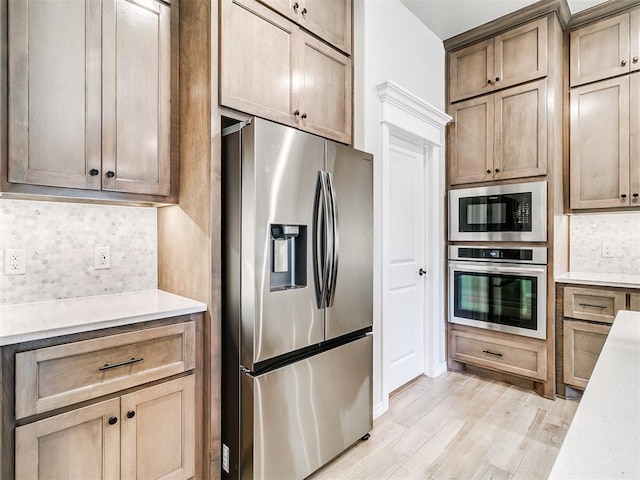 kitchen with light hardwood / wood-style floors, stainless steel appliances, and tasteful backsplash