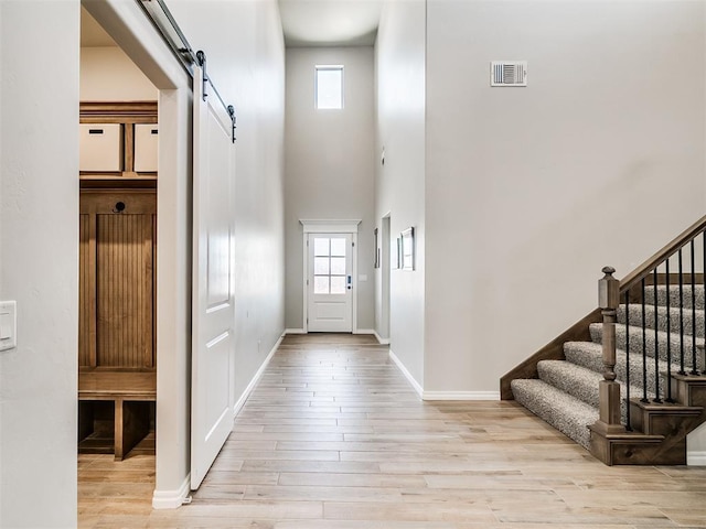 entrance foyer with a barn door, light wood-type flooring, and a high ceiling