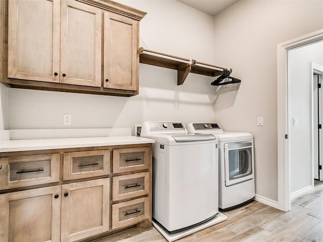 clothes washing area featuring cabinets, light hardwood / wood-style flooring, and independent washer and dryer