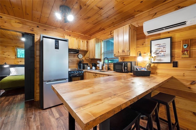 kitchen featuring an AC wall unit, wooden counters, wood walls, black appliances, and wood ceiling