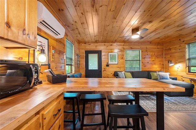 dining room featuring wood walls, plenty of natural light, and a wall mounted air conditioner