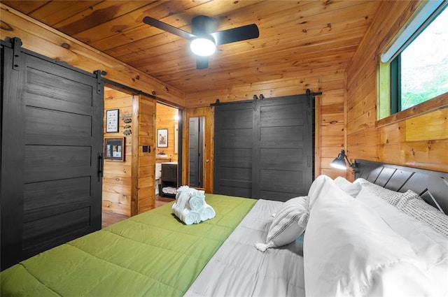 bedroom featuring ceiling fan, wooden ceiling, a barn door, and wood walls