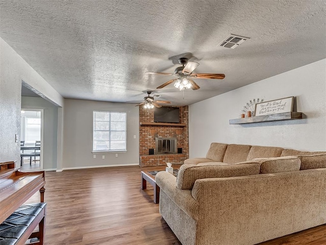 living room with a textured ceiling, a fireplace, hardwood / wood-style floors, and ceiling fan