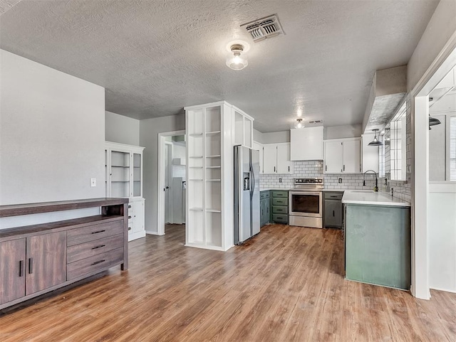 kitchen with stainless steel appliances, sink, white cabinetry, hardwood / wood-style floors, and backsplash