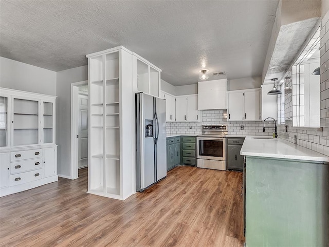 kitchen with appliances with stainless steel finishes, premium range hood, hardwood / wood-style flooring, white cabinets, and sink