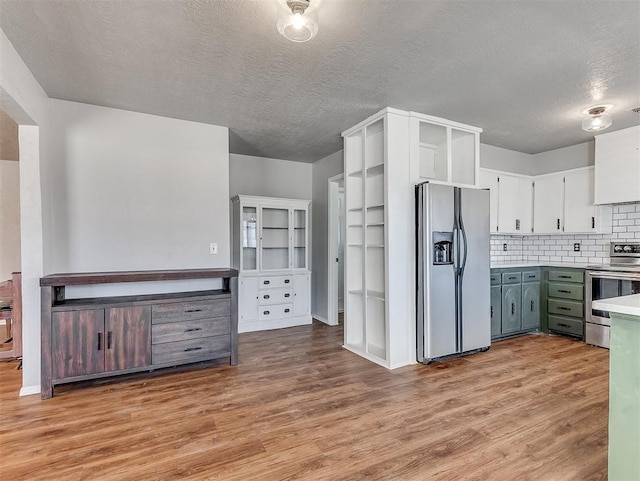 kitchen featuring stainless steel appliances, light wood-type flooring, white cabinets, and tasteful backsplash