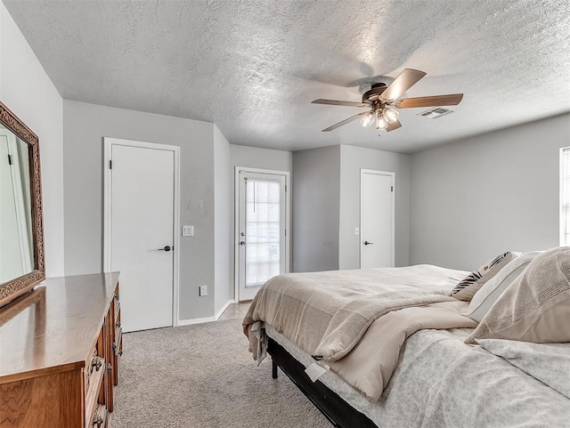 bedroom with a textured ceiling, ceiling fan, and light carpet