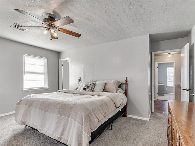 bedroom featuring ceiling fan, light carpet, and a textured ceiling