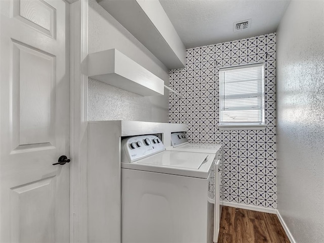 clothes washing area with a textured ceiling, dark hardwood / wood-style flooring, and washing machine and clothes dryer