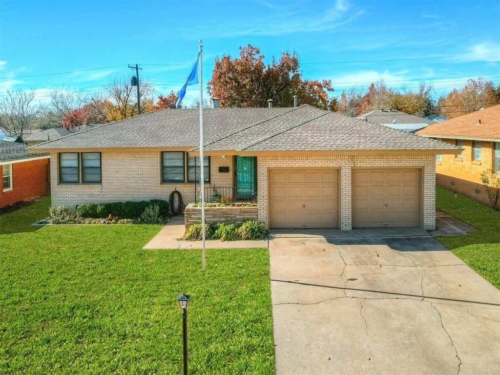 ranch-style house featuring a garage and a front lawn