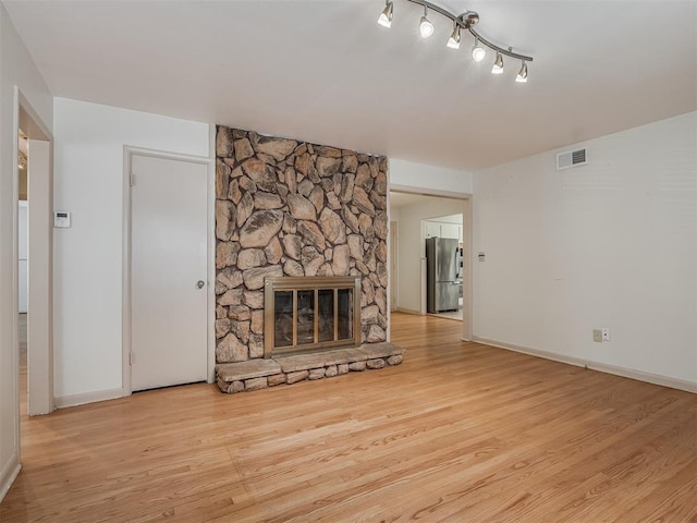 unfurnished living room featuring rail lighting, light wood-type flooring, and a fireplace