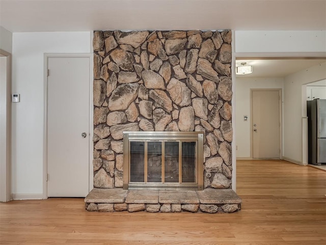 unfurnished living room featuring a stone fireplace and light hardwood / wood-style flooring