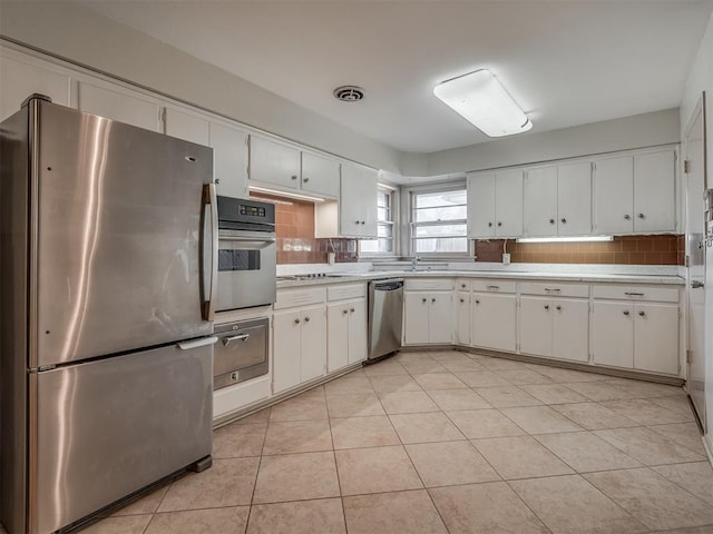 kitchen featuring white cabinets, appliances with stainless steel finishes, and tasteful backsplash