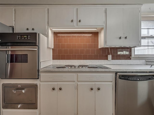 kitchen with backsplash, white cabinets, and stainless steel appliances