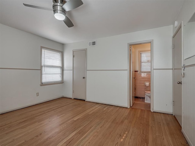 unfurnished bedroom with ensuite bathroom, a closet, ceiling fan, and light wood-type flooring