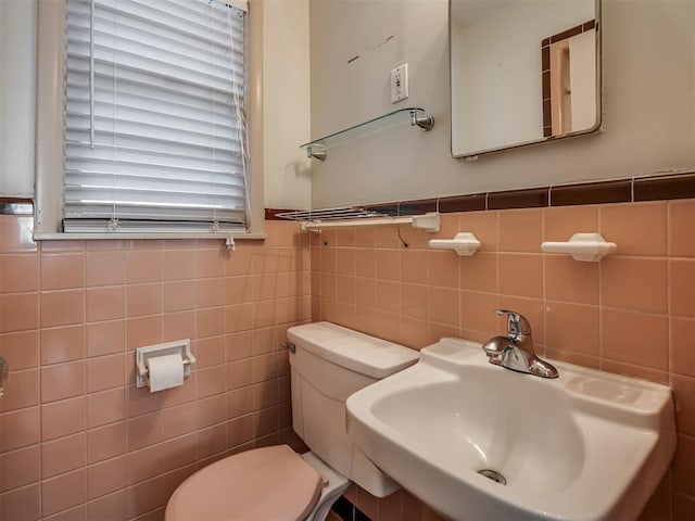 bathroom featuring toilet, tile walls, and sink