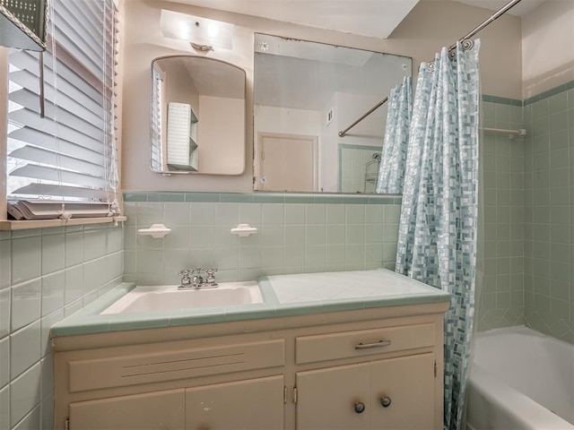 bathroom with shower / bath combo, vanity, and tile walls