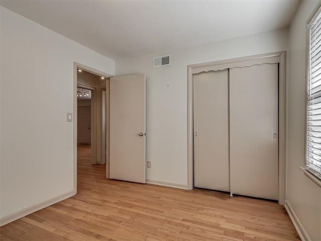 unfurnished bedroom with light wood-type flooring and a closet