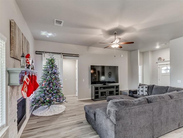 living room with ceiling fan, light hardwood / wood-style floors, and a barn door