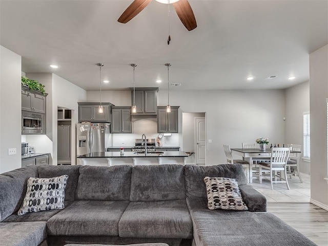 living room featuring light wood-type flooring, ceiling fan, and sink