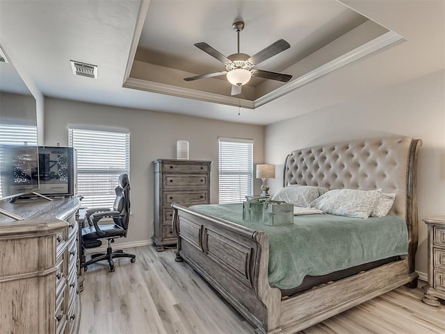 bedroom featuring a raised ceiling, ceiling fan, and light hardwood / wood-style flooring